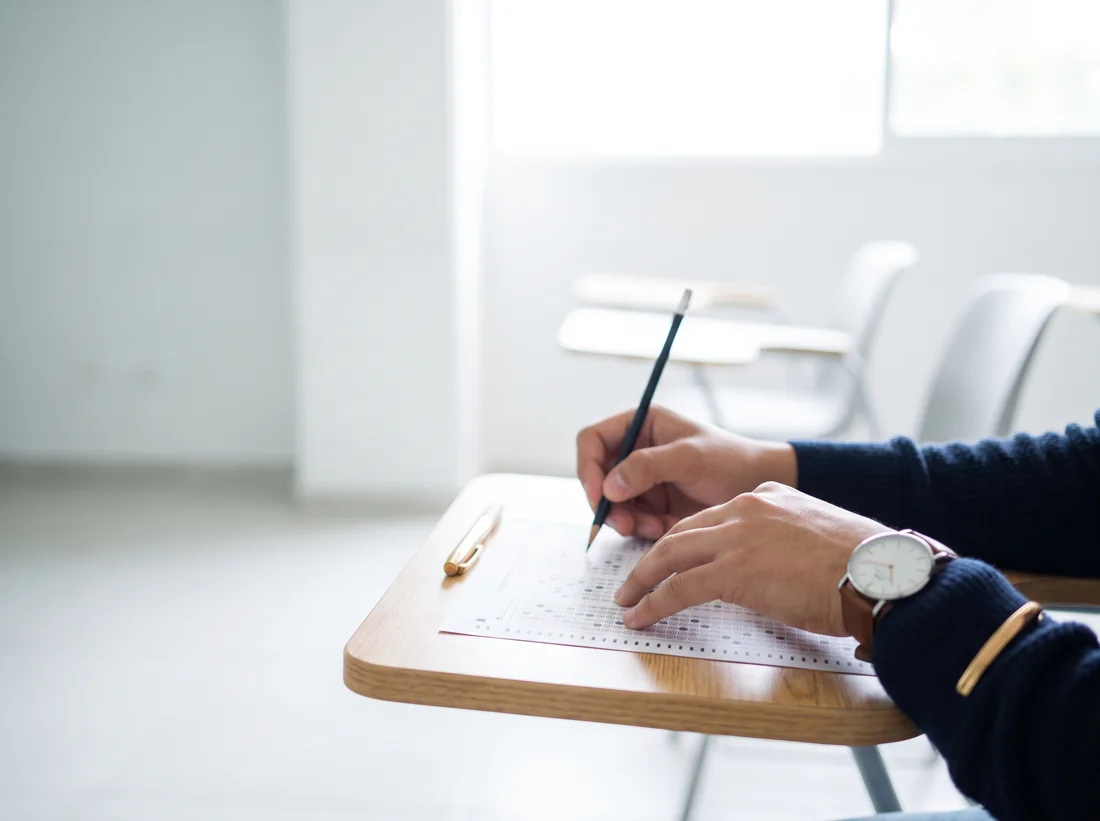 Alumno llenando una hoja de respuestas en un examen psicométrico